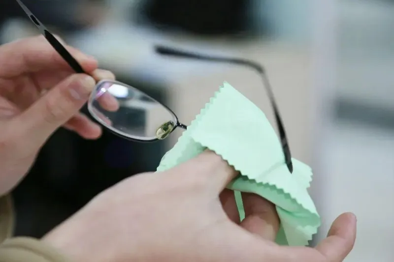 Real close-up of eyeglasses being handled with a microfiber cleaning cloth